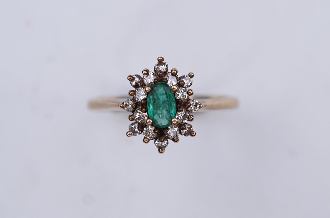 An emerald and diamond cluster ring